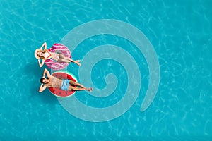 Couple with inflatable rings in swimming pool, top view and space for text. Summer vacation
