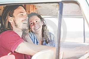 Happy couple inside minivan doing a adventure road trip - Woman with freckles having fun on summer vacation traveling with her