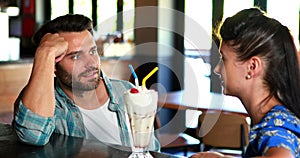 Happy couple interacting while having milkshake