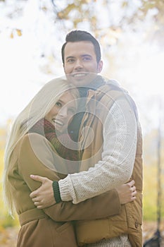 Happy couple in jackets hugging in park