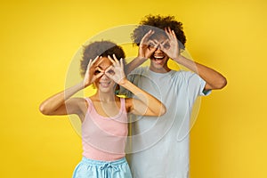 Happy couple joke by making glasses with their hands