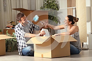 Happy couple joking unboxing belongings moving home photo