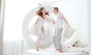 Happy couple jumping and having fun in bed