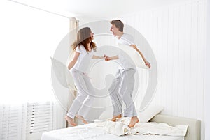 Happy couple jumping and having fun in bed