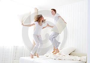 Happy couple jumping and having fun in bed