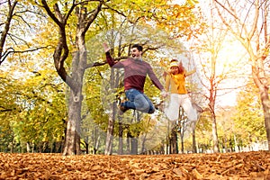 Happy couple jumping in a park in autumn