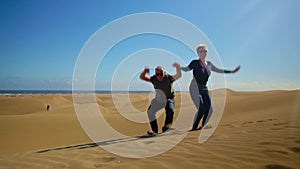 A happy couple jumping in slow motion on desert of Gran Canaria, Spain