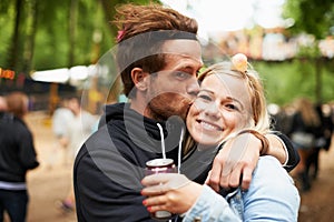 Happy couple, kiss and outdoor festival for love, care or support at party, DJ event or music. Portrait of man hug woman