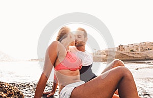 Happy couple kissing on the beach at sunset - Young lovers having romantic tender moments on summer time