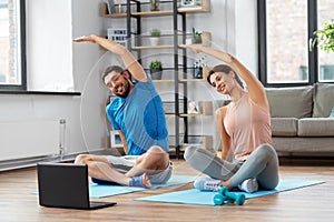 Happy couple with laptop exercising at home