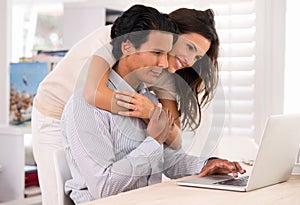 Happy couple, laptop and hug at table in home for remote work, internet or social media. Computer, man and woman embrace