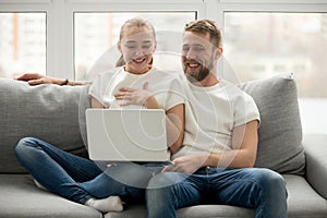 Happy couple laughing with joy looking at laptop at home