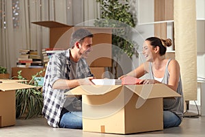 Happy couple laughing unboxing belongings moving house photo