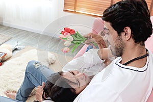 Happy couple in living room, woman lying on the lap of her boyfriend while he is sitting on sofa. Relaxing Lover showing love