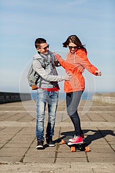 Happy couple with longboard riding outdoors