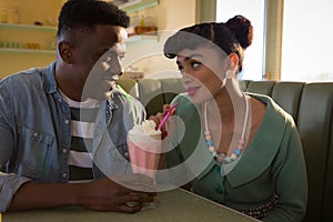 Happy couple looking at each other while having milkshake