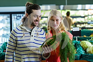 Happy couple looking at fennel in organic section