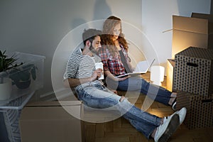 Happy couple looking at photo album while furnishing new home af photo