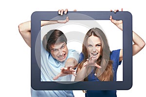 Happy couple looking through tablet frame