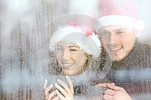 Happy couple looking through a window in christmas