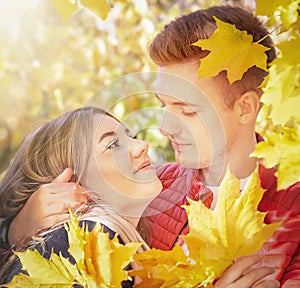 Happy couple in love in autumn yellow maple leaves. Sensual portrait of young woman and man in fall. Love, relationship, family.