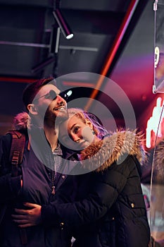 Attractive couple in love. A beautiful girl hugging her boyfriend standing in the night on the street.