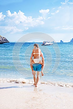 Happy couple in love boyfriend carrying his girlfriend in sea on tropical beach