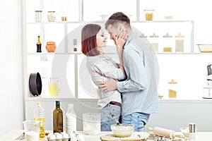 Happy Couple in love cooking dough and kissing in kitchen