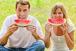 Happy couple in love eating watermelon outdoors in summer park