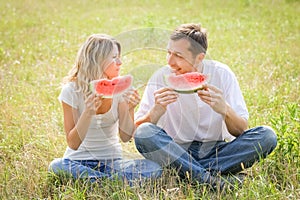 happy couple in love eating watermelon outdoors in summer park