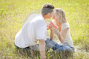 happy couple in love eating watermelon outdoors in summer park