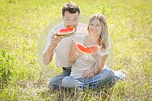 happy couple in love eating watermelon outdoors in summer park