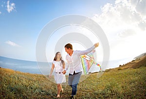 Happy couple in love with flying a kite on the beach