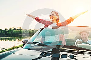 Happy couple in love go by cabriolet car in sunset time