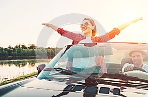 Happy couple in love go by cabriolet car in sunset time