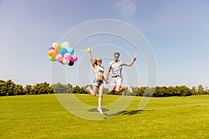 Happy couple in love having fun and jumping with balloons