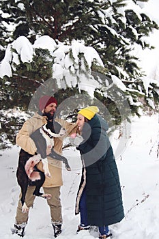 Happy couple in love having fun in the snow with his baby dog