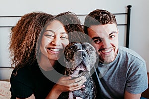 happy couple in love at home. Afro american woman, caucasian man and their pit bull dog together. Family concept