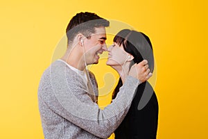 Happy couple in love kissing while listening to the musicover over yellow