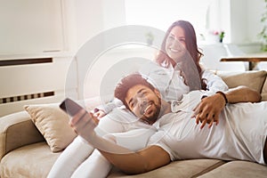 Happy couple lying on sofa together and relaxing at home