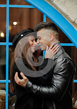 Happy couple in love in the rain. Beautiful girl hugs her boyfriend on a background of blue windows