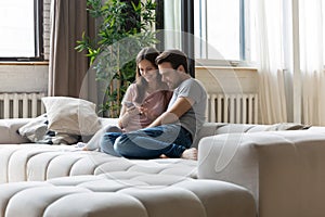 Happy couple in love relaxing on couch, using phone together