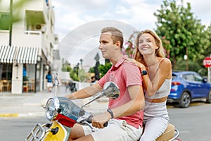 Happy couple in love riding a motorbike on summer city streets ,man and woman travel . Young riders enjoying themselves