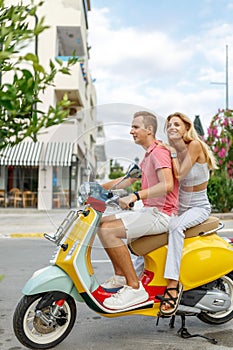 Happy couple in love riding a motorbike on summer city streets ,man and woman travel . Young riders enjoying themselves
