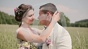 Happy couple in love share intimate moment standing in a wheat field on a wedding day. Bride and groom tenderly kissing.