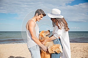 Happy couple in love sitting on the beach with dog