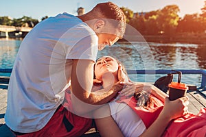 Happy couple in love sitting by the river, hugging and kissing