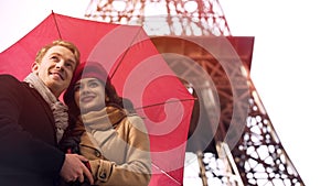 Happy couple in love standing under umbrella in Paris, having romantic vacation