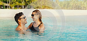 happy couple in love swimming in the ocean by tropical white sand beach. romantic getaway. banner with copy space