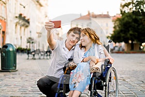 Happy couple in love taking selfie on the old city background - Disability concept with woman on wheelchair.